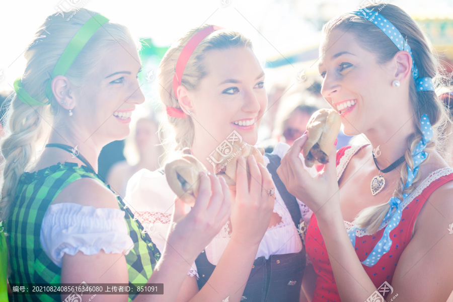 朋友们穿着民族服装一起参观巴伐利亚博览会，吃面包卷烤香肠