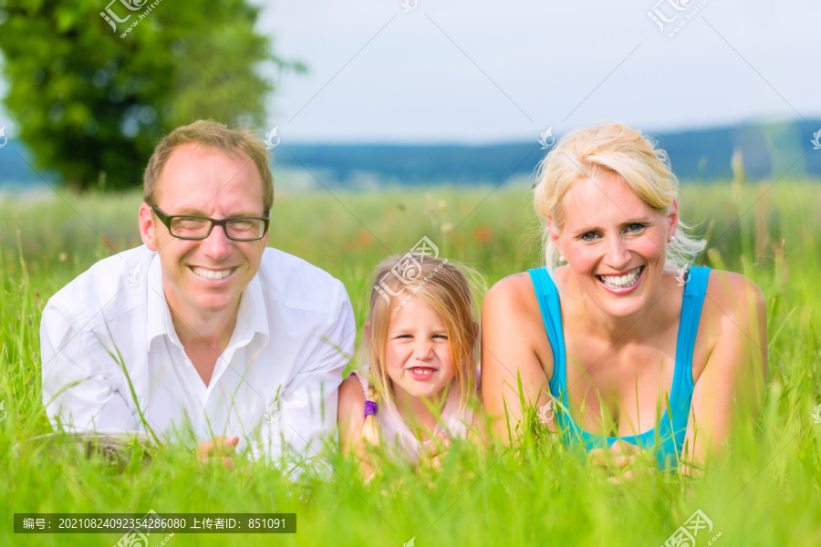 家人、父母和女儿躺在草坪或田野的草地上