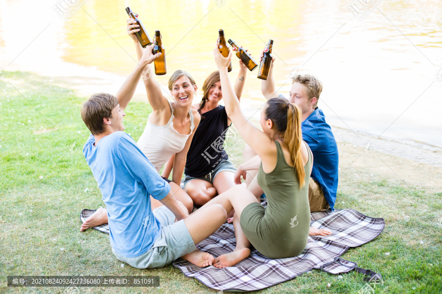 公园里的学生们在河边野餐时用啤酒瓶敬酒