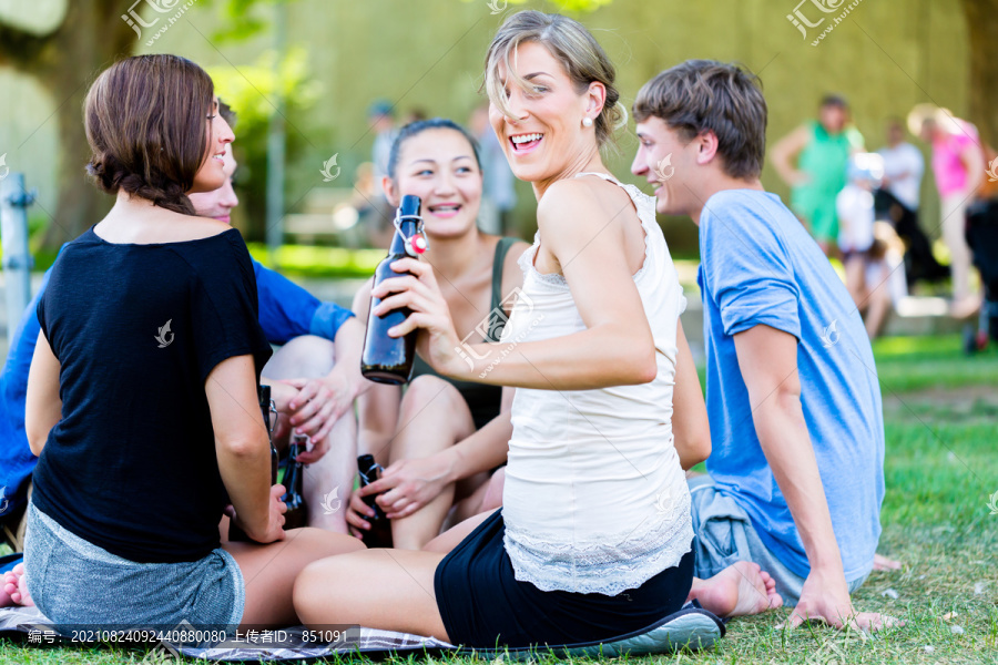 公园里的学生喝着啤酒，在河边野餐时聊天