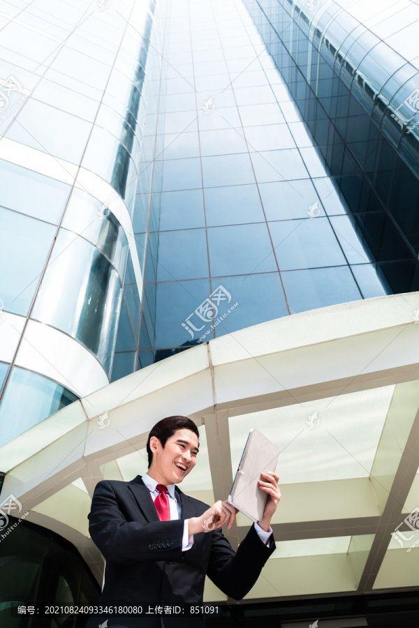 亚洲商人在塔楼前的平板电脑上查看外部邮件