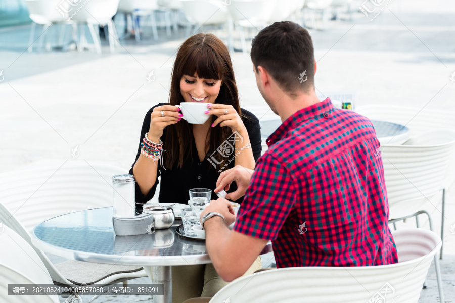 快乐的年轻夫妇在户外咖啡馆喝咖啡