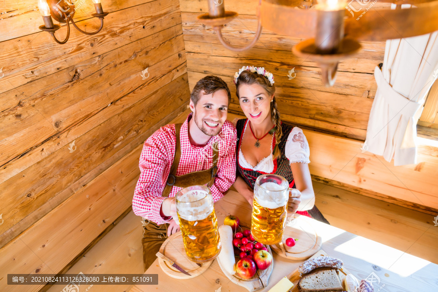 这对夫妇在阿尔卑斯山的山间小屋吃晚餐，喝啤酒，吃冷盘