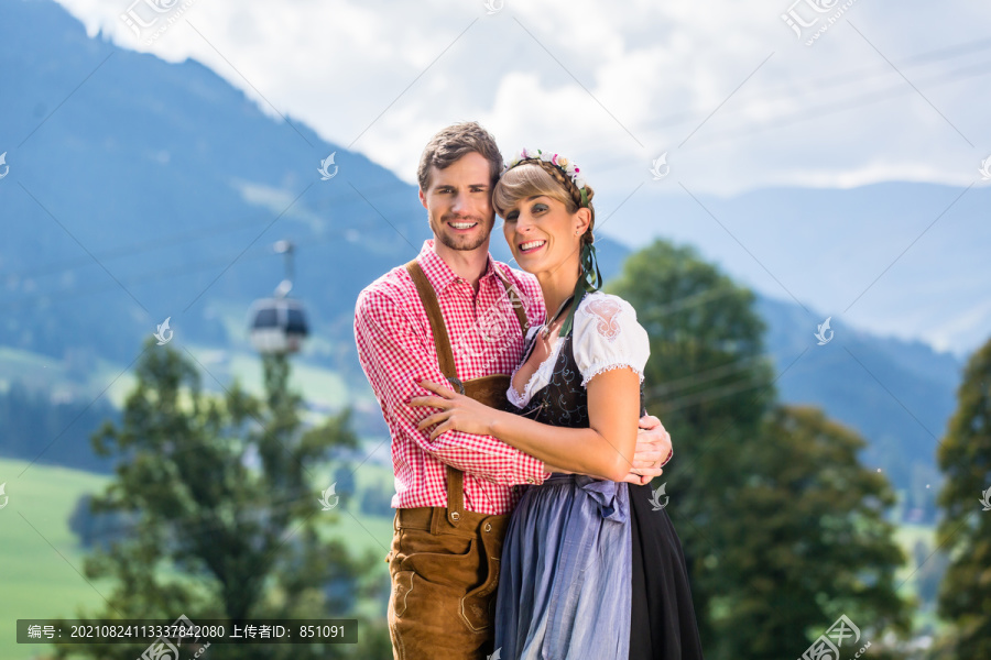 特拉希特的一对夫妇站在阿尔卑斯山的草地上，背景是一辆缆车