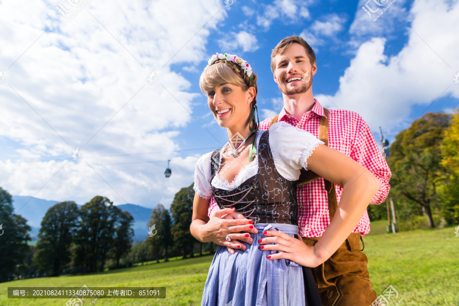 特拉希特的一对夫妇站在阿尔卑斯山的草地上，背景是一辆缆车