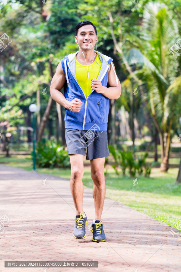 亚洲男子在热带公园慢跑或跑步健身