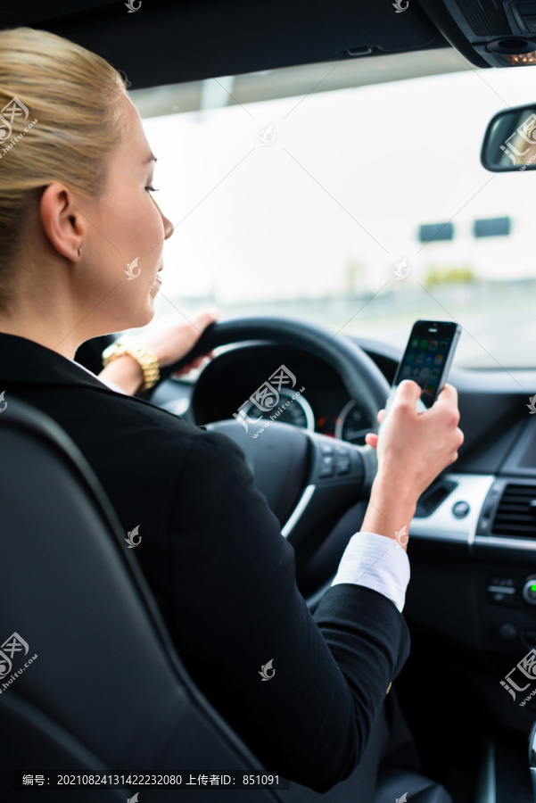 这位女士一边开车一边发短信，一边愤怒地看着他的手机，而不是交通工具
