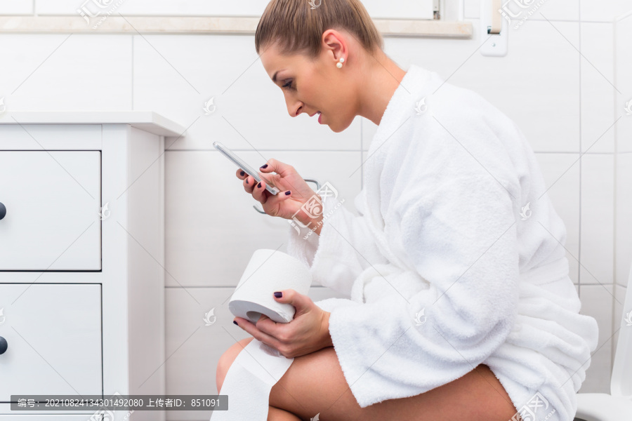 坐在卫生间里用手机写短信的女人