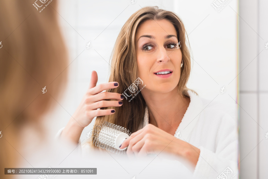 金发女人在浴室镜子前梳头