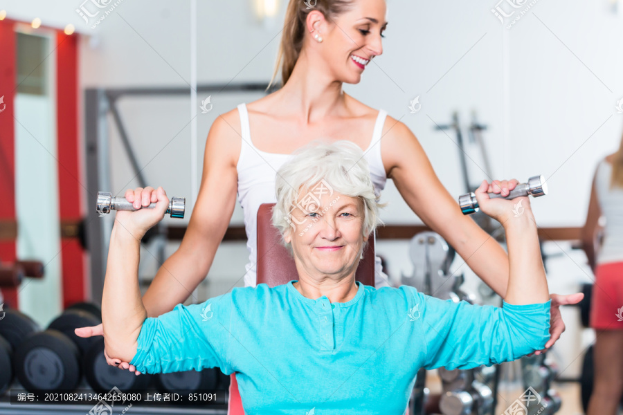高级女子健身教练在健身房举重哑铃进行胸肌训练作为运动锻炼