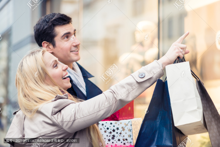 一对夫妇在商店橱窗里买圣诞礼物，男人和女人