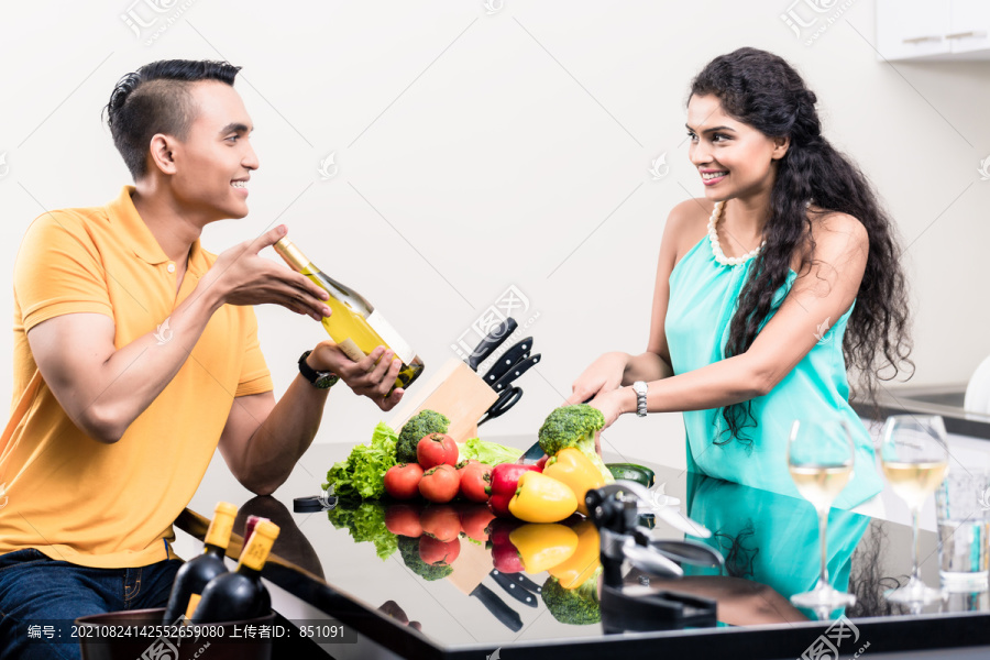 印度女人和男人在厨房里用红酒做沙拉