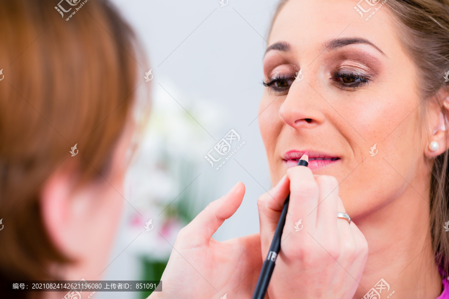 美容师在美容院给女性涂唇彩