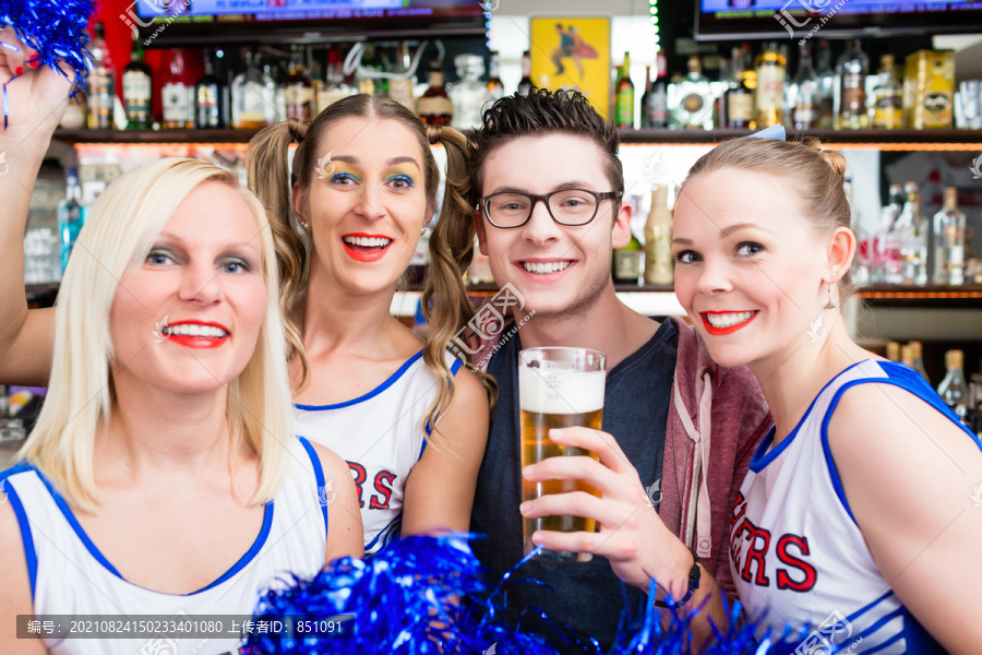 体育队的球迷在酒吧里喝啤酒观看比赛