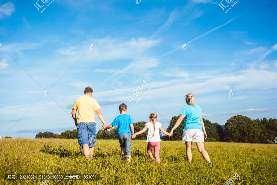 一家人手牵着手在草地上奔跑，母亲、父亲和孩子们