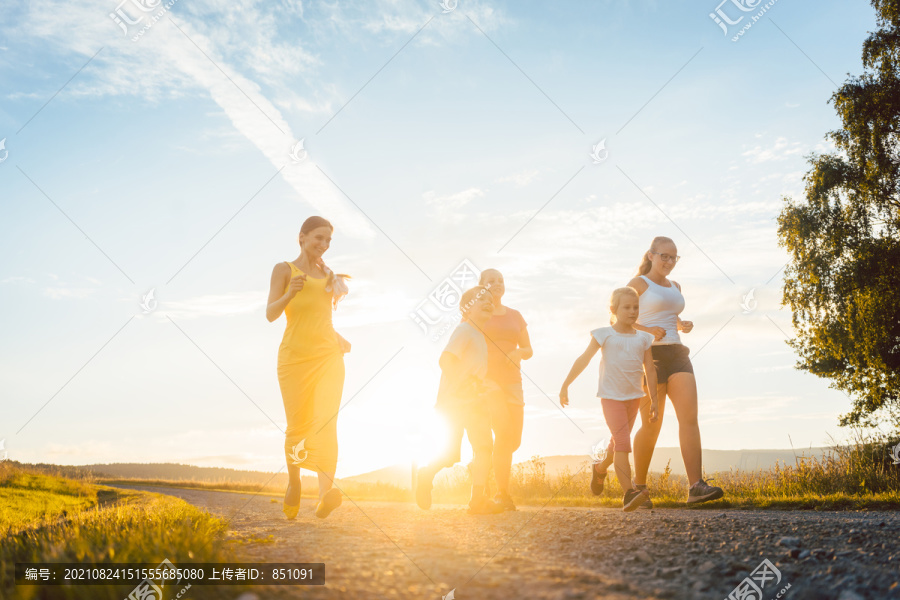 在背光的夏日景观中，一家人在小路上嬉戏奔跑