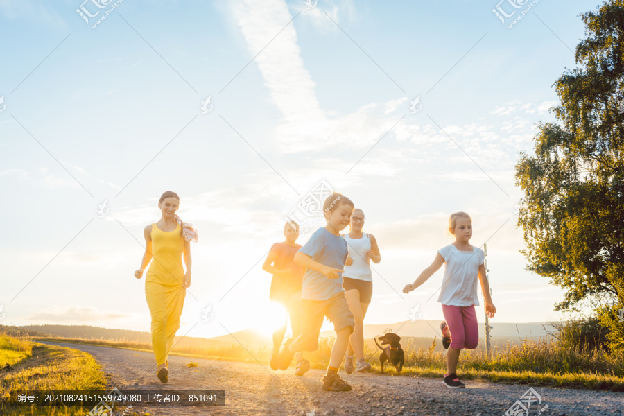 在背光的夏日景观中，一家人在小路上嬉戏奔跑