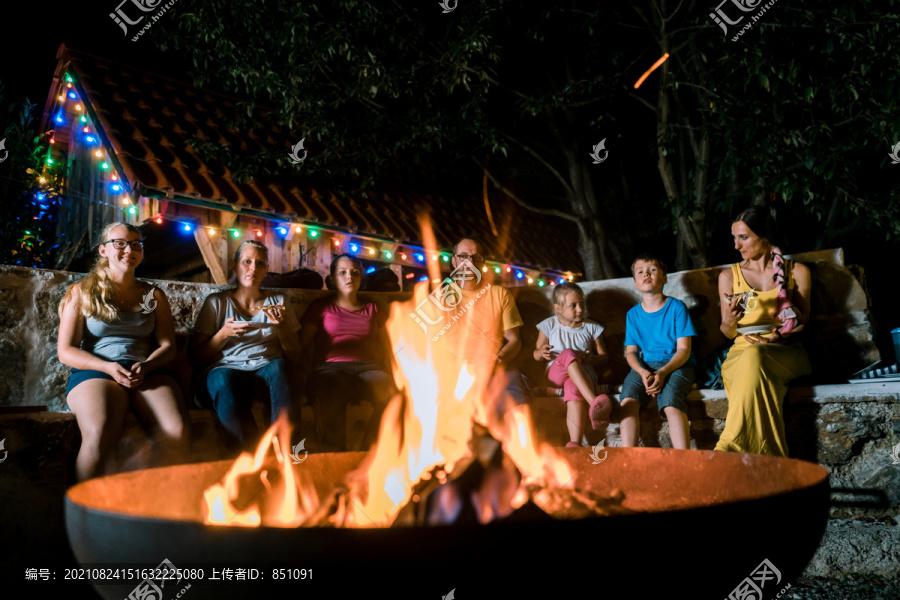 一家人晚上坐在火炉前举行烧烤聚会