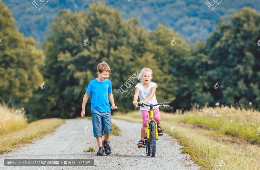 小男孩和小女孩在土路上散步和骑自行车
