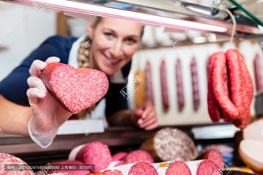 肉店女售货员向顾客展示心形香肠