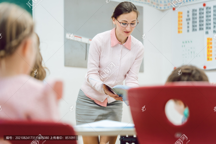女教师在教室里与学生交谈，分发考试成绩