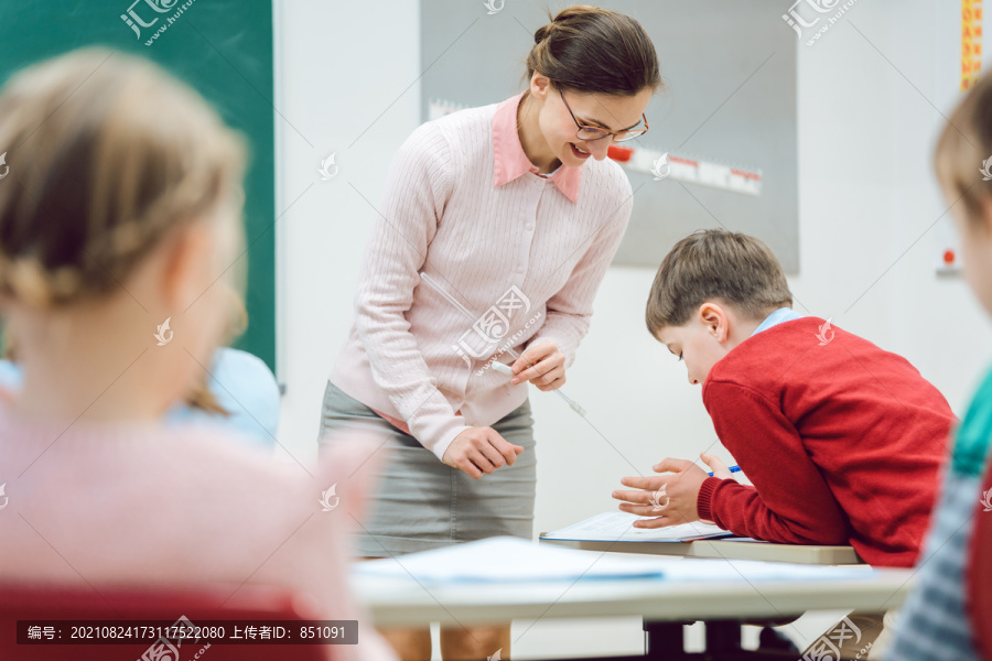 女教师在教室里与学生交谈，分发考试成绩