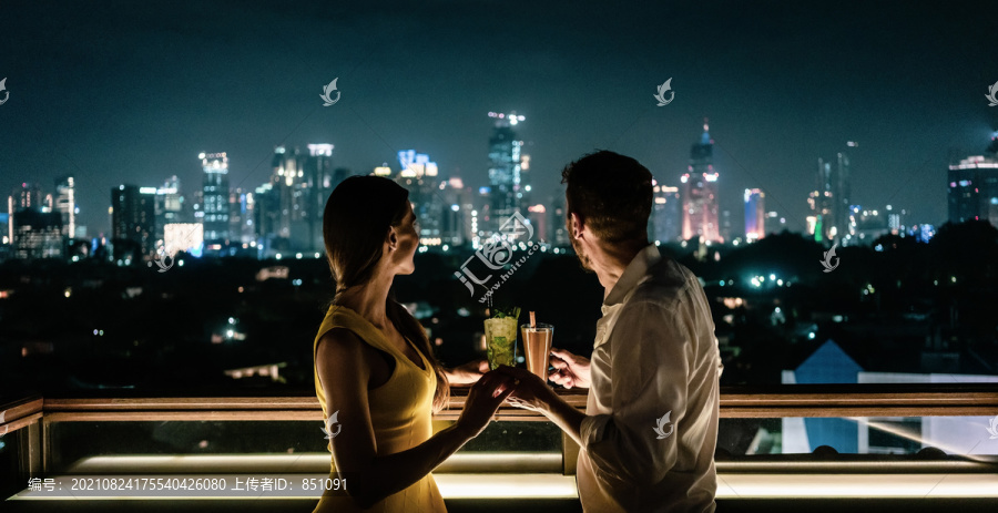 夫妇俩在俯瞰城市天际线的屋顶露台上喝酒