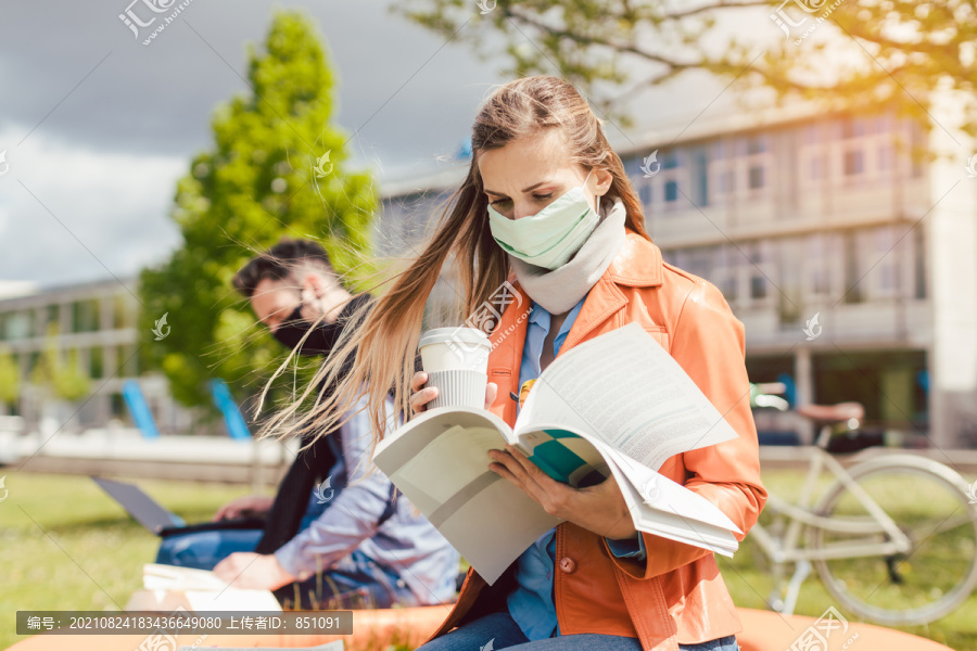 大学校园里的一名女学生在使用笔记本电脑时正在学习戴口罩