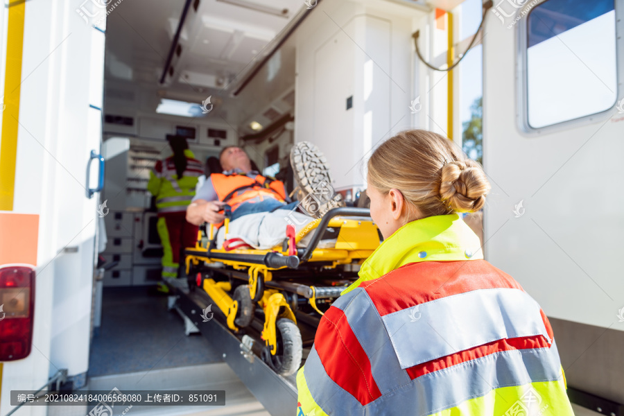 身穿制服的医护人员将受伤男子放在救护车的担架上
