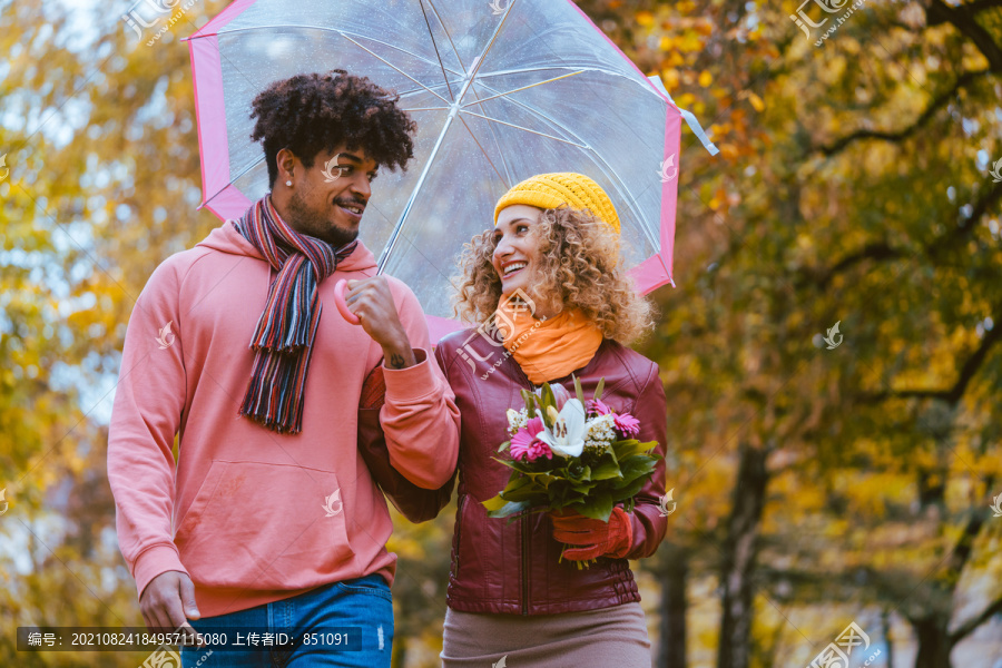 不同种族的夫妇在充满秋天色彩的公园里散步
