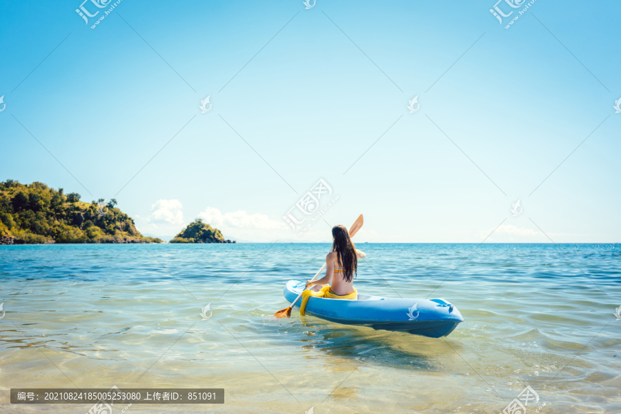在清澈的海水中划着皮划艇享受夏天的女人