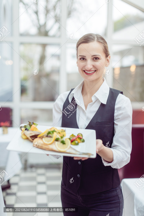 一家好餐馆的女服务员向镜头展示一道美味佳肴