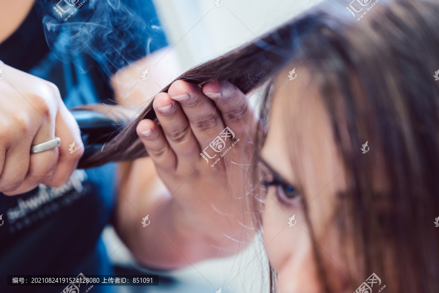 美发师在女顾客的头发上使用扁铁，特写镜头