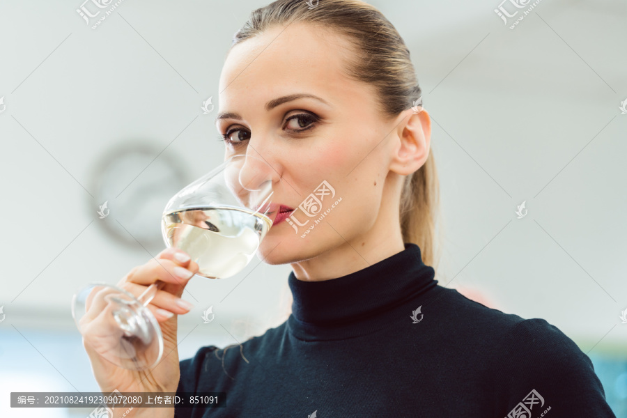 下班后喝一杯白葡萄酒的女人看着镜头