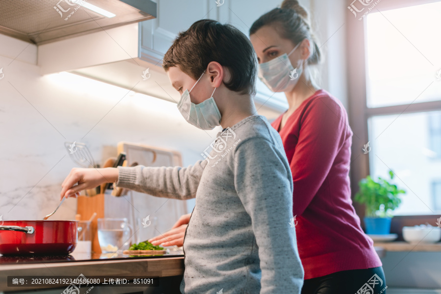 危机期间，母子俩戴着口罩在家做饭