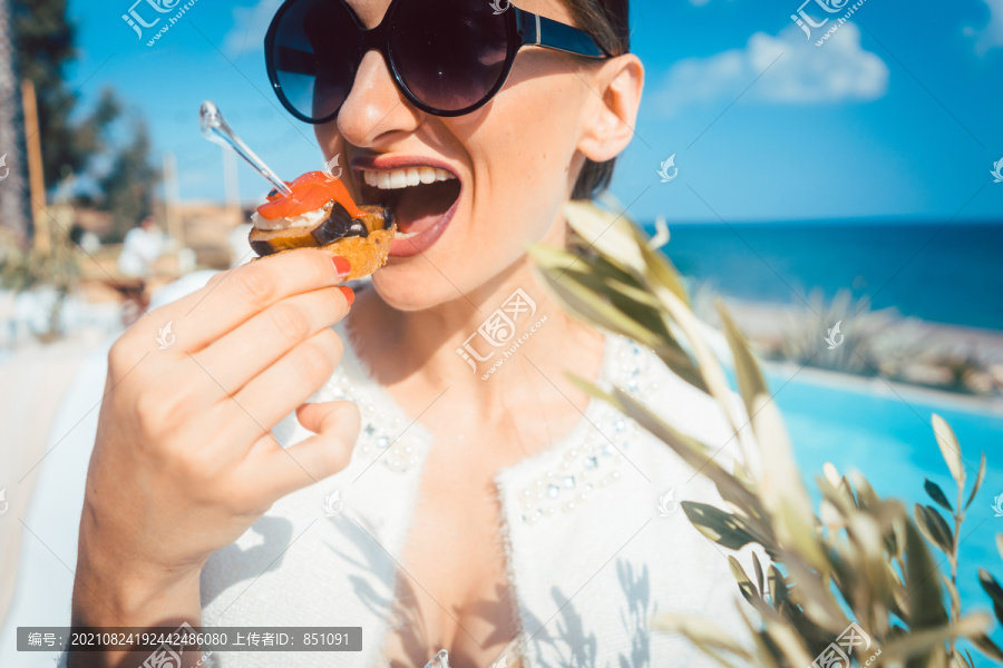 在游泳池旁的海滨别墅的泳池餐饮处享用食物的妇女