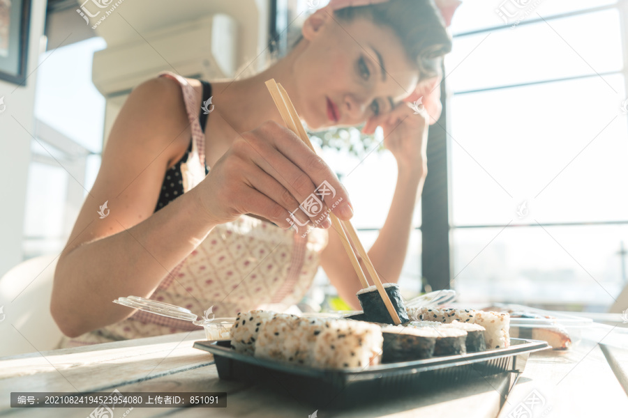 考虑到自己的生活，一位家庭主妇正在做家务休息，吃着寿司