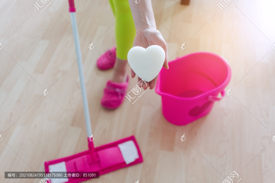 特写镜头：一个真正爱上拖地和清洁的女人，展示了一块心形海绵