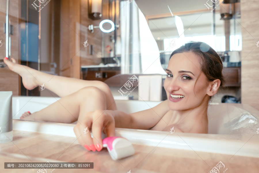 在酒店浴缸里洗澡的女人抓着剃须刀去腿毛