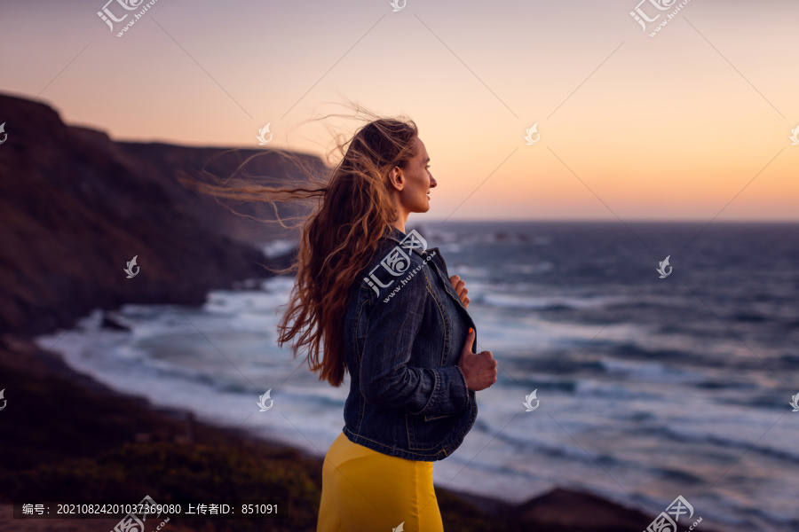 日落海滩上的女人，头发上的风是自由的