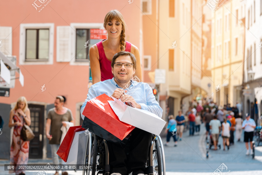 一名坐轮椅的男子在购物途中被他的朋友推着提包