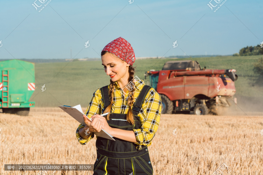 armer拿着剪贴板在麦田上记下正在收割的小麦