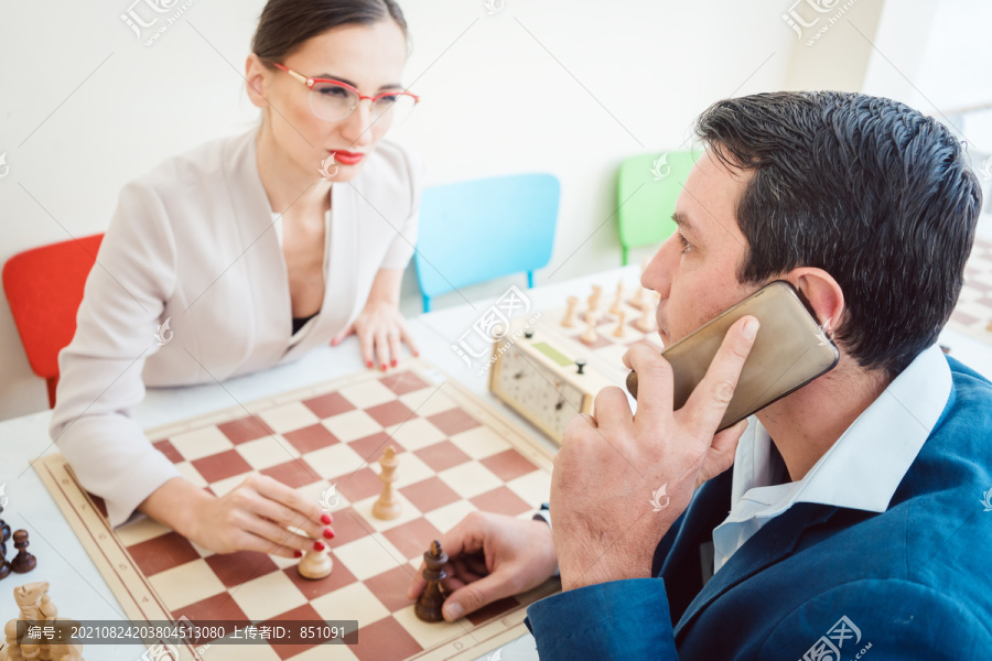 生意人和打电话的男人下棋，女人在等他继续