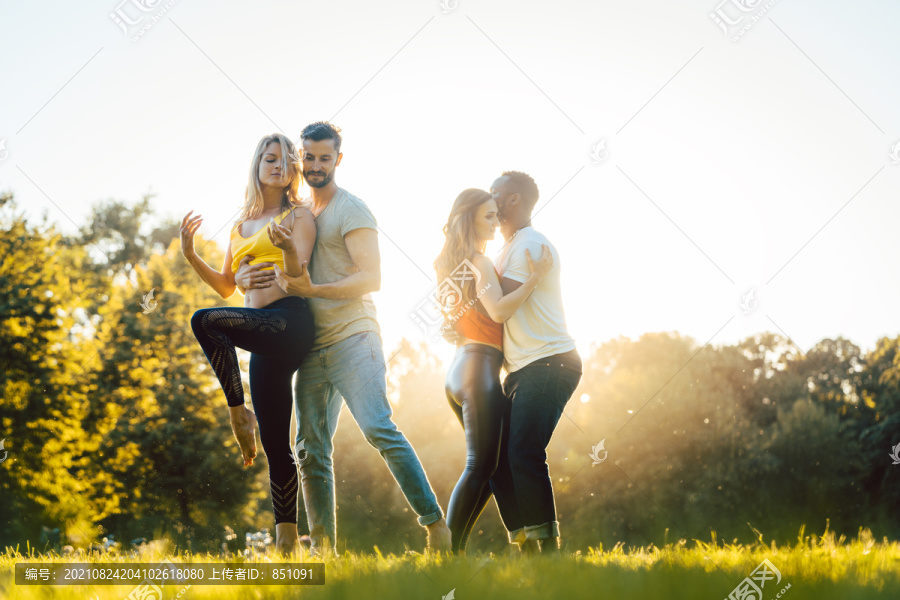 日落时分，两对情侣在公园里进行高级舞蹈动作