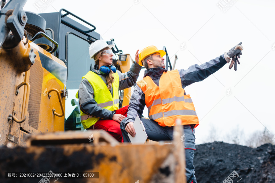 采石场挖掘机上的工人指着东西