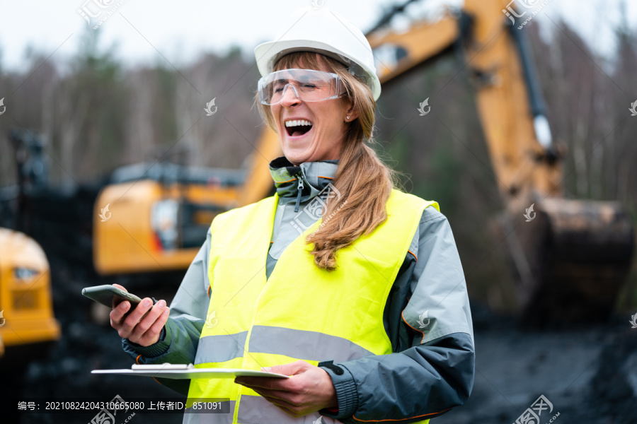 露天采矿中的女工使用电话与经理交谈