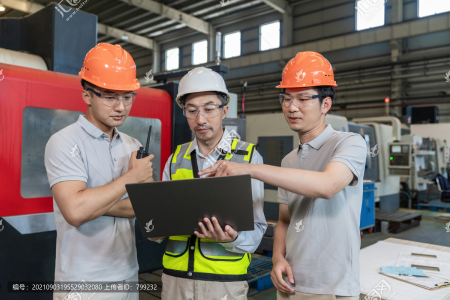 三个工程师穿保护工作服戴着安全帽在工厂工作