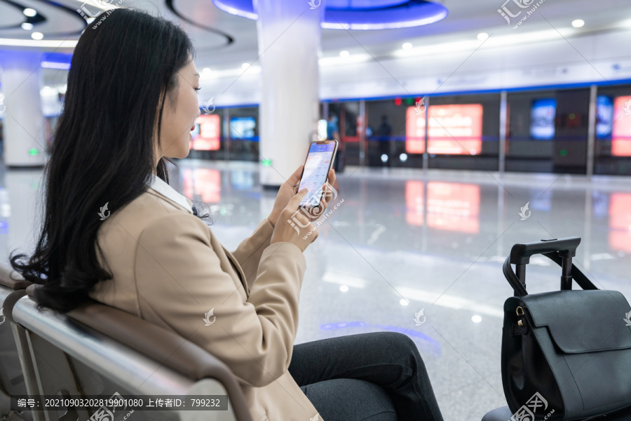 商务女士在机场坐着使用手机