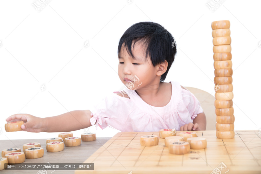 小女孩桌子上摞中国象棋棋子