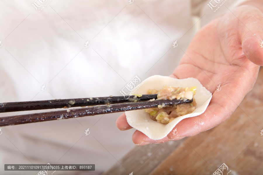 筷子夹着肉馅放进饺子皮里包饺子